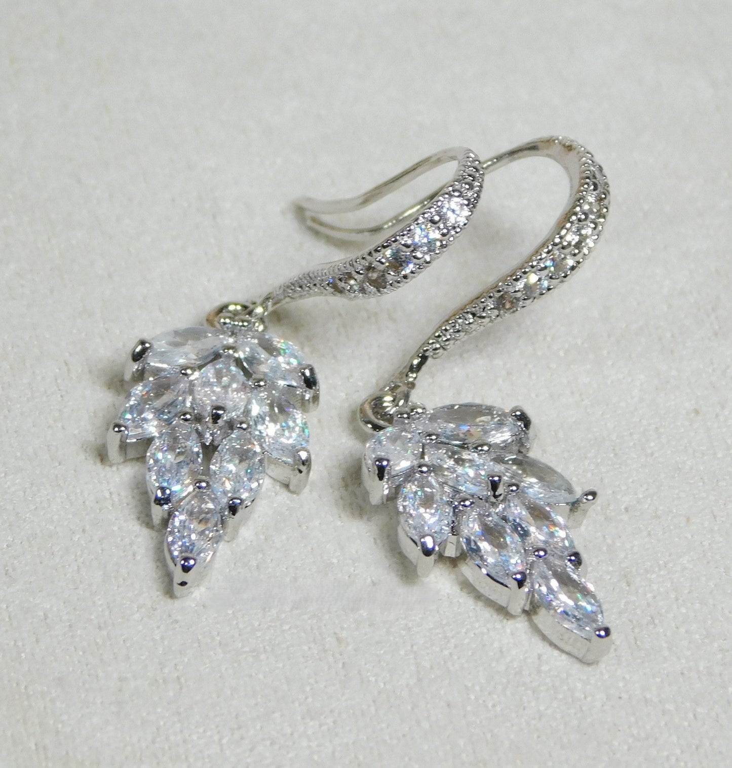 Cubic Zirconia sparkling leaf dangle earrings with rhodium-plated hooks.