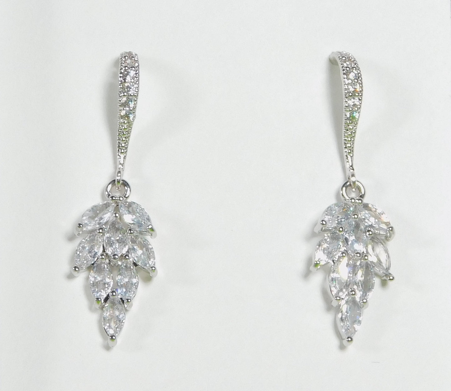 Cubic Zirconia sparkling leaf dangle earrings with rhodium-plated hooks.