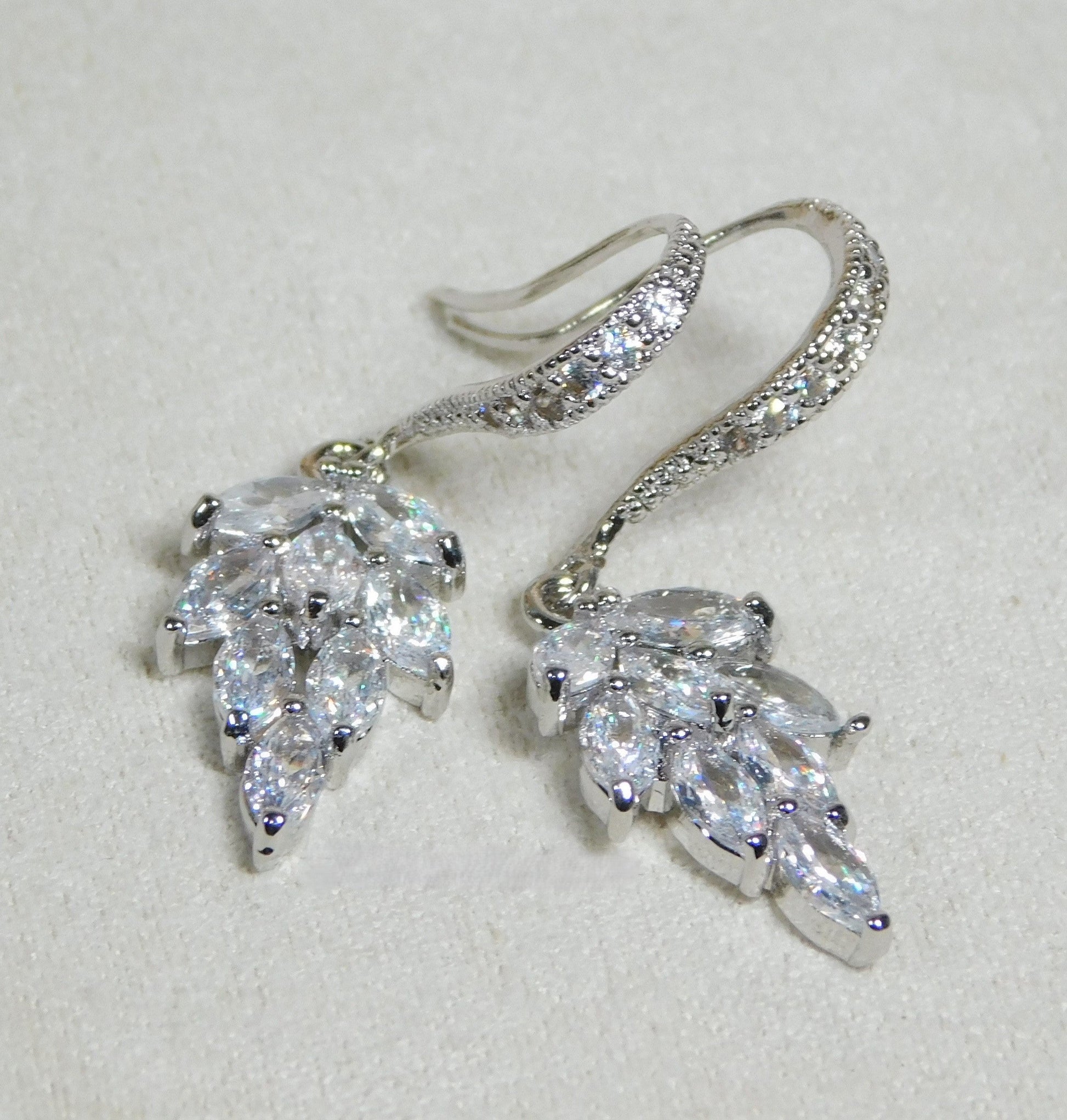 Cubic Zirconia sparkling leaf dangle earrings with rhodium-plated hooks.